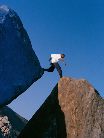 Confident Young Man Bridging Granite Boulders in Desert Landscape