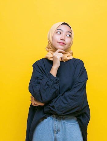 Contemplative Young Woman in Hijab on Yellow Background