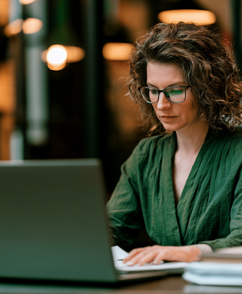 Focused Woman Writer Reviewing Document on Laptop