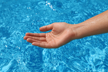 Relaxed Hand Above Vivid Blue Pool Water