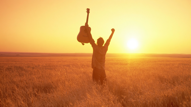 Celebratory Guitarist in Wheat Field at Sunset