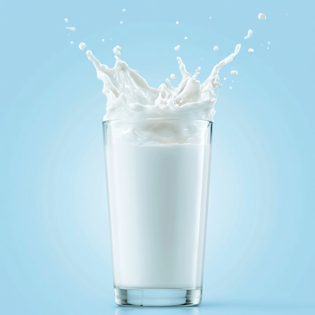 Dynamic Milk Splash in Glass against Sky Blue Background