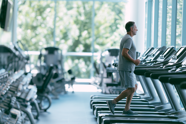 Focused Man Running on Treadmill in Modern Fitness Gym
