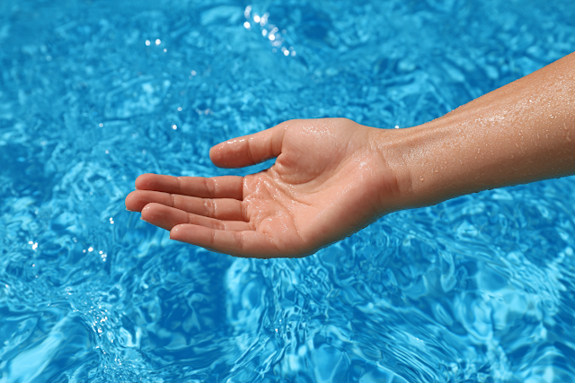 Relaxed Hand Above Vivid Blue Pool Water
