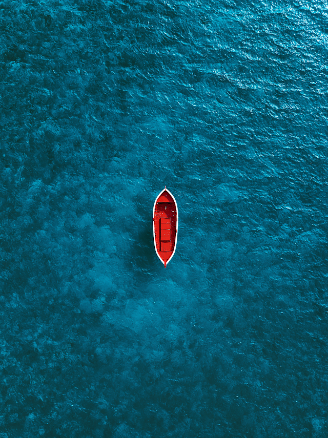 Serene Aerial View of a Red Boat on Crystal Clear Water