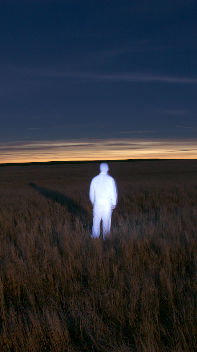 Solitary Luminous Figure in Wheat Field at Dusk