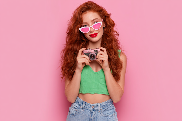 Stylish Young Woman with Camera Against Pink Background